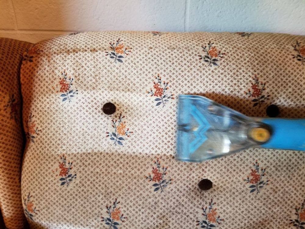 A floral sofa cushion being cleaned with a hand tool