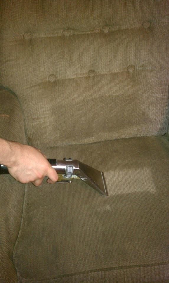 A person using an upholstery tool on the seat of a chair